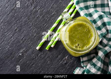 Healthy green smoothie in jar on black stone. Top view. Copy space Stock Photo