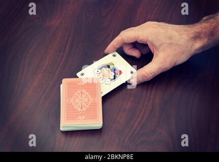 hand picking up a joker in pack of playing cards Stock Photo