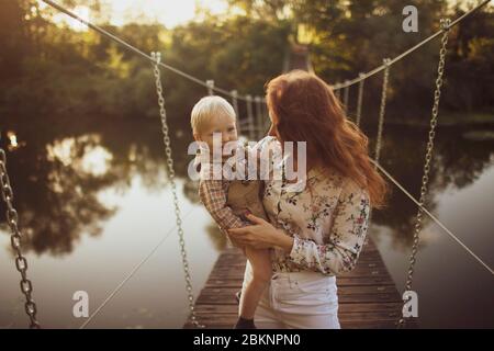 Mother and child walking on a suspension bridge. Stock Photo