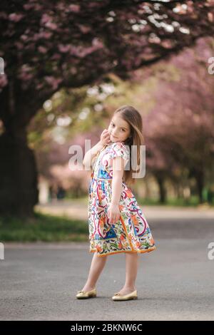 Full length of beautiful little girl in dress standing and posing over blue  background Stock Photo - Alamy