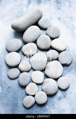 Grey and white pebbles on a grey background. Stock Photo