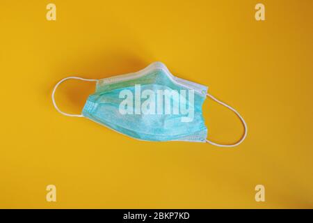 medical or surgical mask - used disposable protective face mask on yellow background Stock Photo