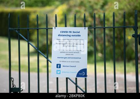 Merton, London, UK. 5 May 2020. Sunshine after a hazy start in London with local people maintaining social distancing while taking exercise. Social Distancing notice on a park gate. Credit: Malcolm Park/Alamy Live News. Stock Photo