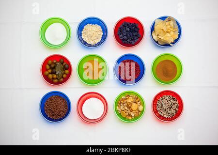 Colorful bowls with a different seasoning, spices and snacks on the white background Stock Photo