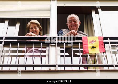 Older couple clapping in the window in support of people against the coronavirus Stock Photo