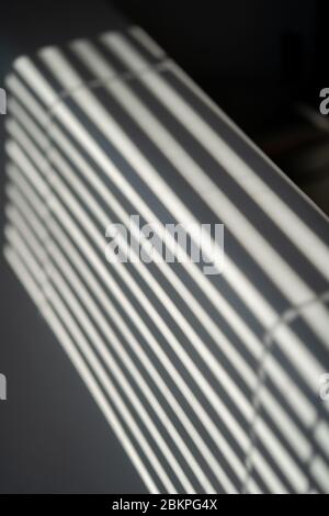Industrial design window sunlight parallel lines shadows. Light and shadow from the window. Thin lines of light on the wall. Shadow from the blinds. Stock Photo