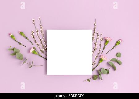 Frame made of eucalyptus and flowers on a purple pastel background. Paper card mockup. Holiday concept. Stock Photo