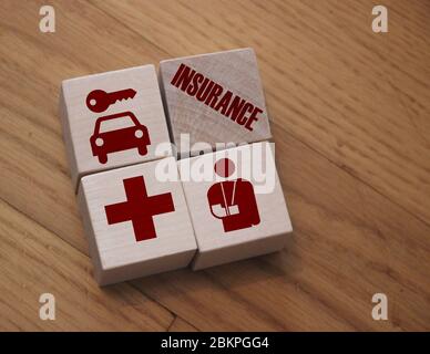 iIsurance word and icons symbolizing risks of illness or injury on 4 wooden cubes. Healthcare and Medicine Insurance Concept Stock Photo