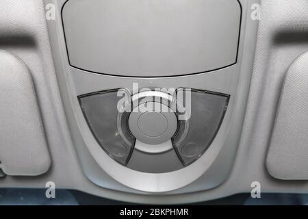 Lighting control inside the car from the top on the instrument panel behind the rear-view mirror in white with buttons. Auto service industry. Stock Photo