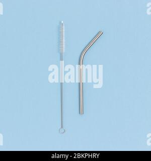 Drink tube and clean brush made of stainless steel on a blue pastel background. Plastic free composition. Stock Photo