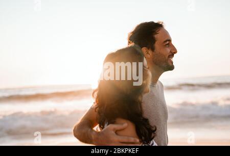 Young couple walking together by the ocean at sunset Stock Photo