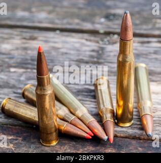 Five different caliber rifle bullets together on a wooden background, three have red tips Stock Photo