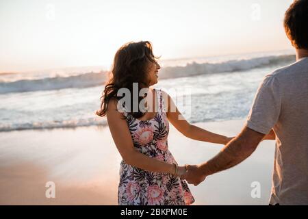 Young couple having fun together on a beach at sunset Stock Photo
