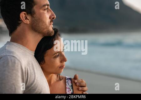 Young couple looking out at the ocean at sunset Stock Photo