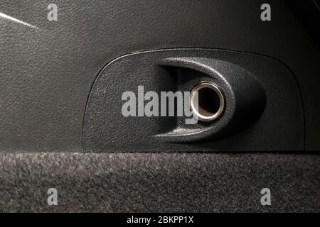 Empty cigarette lighter socket in a car on a black plastic panel. Stock Photo