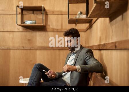 Stylish man sitting in a lounge checking his text messages Stock Photo