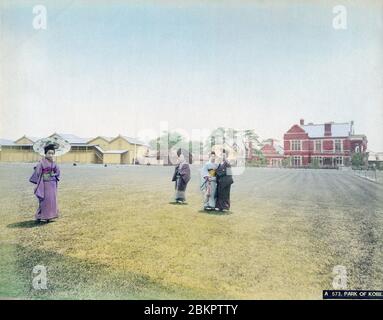 [ 1890s Japan - Recreation Grounds for Foreigners in Kobe ] —   Four Japanese women in kimono at the East Recreation Ground (the current Higashi Yuenchi Park) in Kobe, Hyogo Prefecture.  The brick building in the background is the Kobe Club ( 神戸外人クラブ), an elite club for foreign residents. The club was launched in 1890 (Meiji 23) and designed by British architect Alexander Nelson Hansell (アレクサンダー・ネルソン・ハンセル, 1857-1940).  The building on the left is the Kobe Regatta and Athletic Club (KRAC).  19th century vintage albumen photograph. Stock Photo