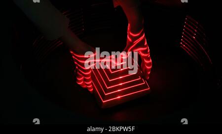 Interactive exposition in science museum - optical illusion with red lasers, woman hand and geometric pyramid figure. Future, experiment and Stock Photo