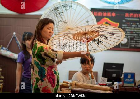 Beijing / China - July 17, 2016: Chinese woman holding decorated Chinese oilpaper umbrella in traditional handicrafts shop in Beijing, China Stock Photo