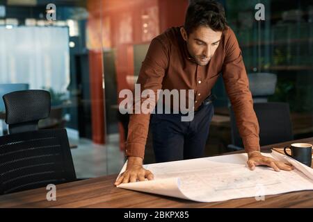 Architect leaning over an office table and reading blueprints Stock Photo