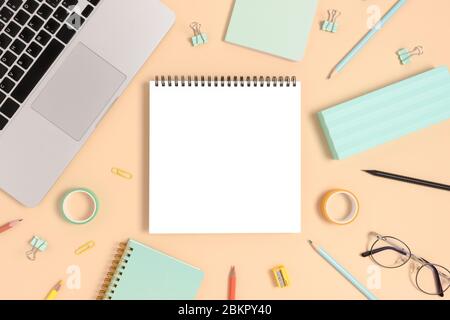 Blank notepad mockup. Top view of laptop and stationery on a yellow pastel background. Workspace concept. Stock Photo