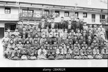 [ 1900s Japan - Japanese School Children ] —   Elementary school students in traditional kimono and hakama posing with their teachers for a formal group photo. Early 1900s.  19th century vintage gelatin silver print. Stock Photo