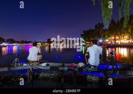 Beijing / China - July 2, 2016: Two night fishermen fishing at the Shichahai lake in central Beijing, China Stock Photo