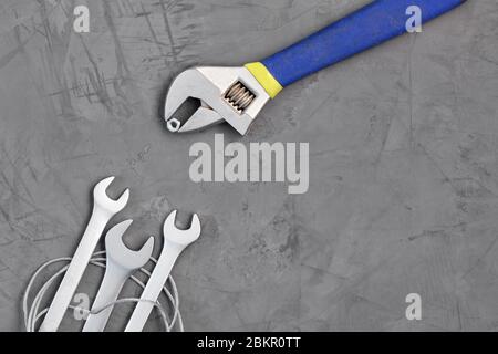 Adjustable wrench feeds a nut new wrenches on a background of gray concrete. The concept of training and development. Stock Photo