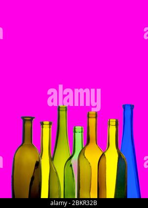 WINE BOTTLES BRIGHT COLOUR COLOURFUL MODERN  glass wine bottles on a vertical format bright magenta colour background, conceptual funky new world poster style cool drinking wines Stock Photo