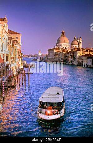 VAPORETTO WATERBUS VENICE Grand Canal with Vaporetto waterbus transport and the timeless sunset view down the Grand Canal to the Basilica di Santa Maria della Salute and its landmark dome Venice Italy Stock Photo