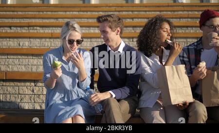 Group of students sitting in campus and eating. Stock Photo