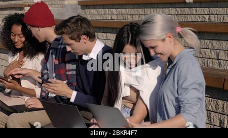 Multiracial friends group share social media news sit together t Stock Photo