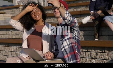 Smiling teenage couple having fun, making selfie photos on smart Stock Photo
