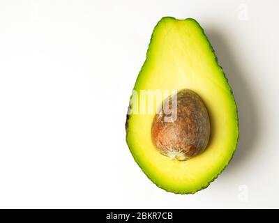 Half an avocado with the stone left in on a white background Stock Photo