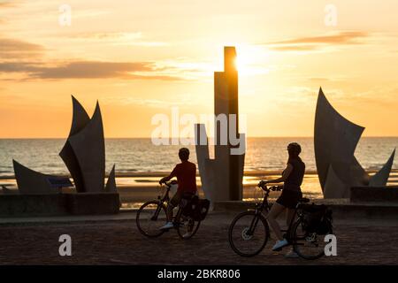 France, Manche, Saint-Laurent-sur-Mer, Sunrise at Omaha beach and cycle tourists along the V?lo Maritime route Stock Photo