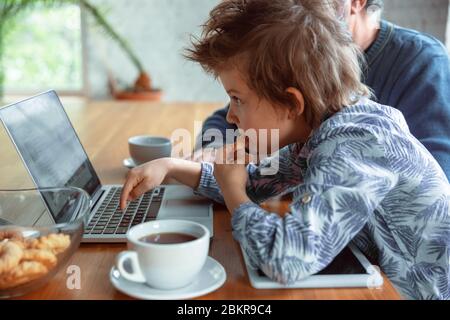 Using devices. Grandfather and his grandson spending time together insulated at home. Having fun, stadying online, reading and cleaning up. Concept of quarantine, family, love, realtions, togetherness. Stock Photo