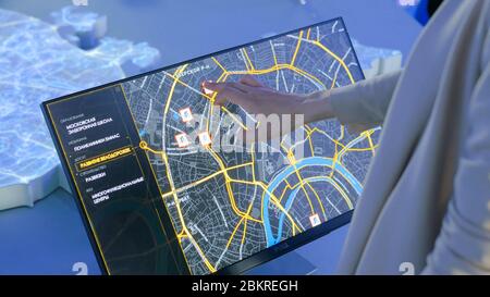 MOSCOW, RUSSIA - July 30, 2018: Smart City Exhibition. Woman using interactive touchscreen display with virtual map of Moscow at modern technology Stock Photo