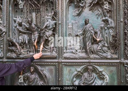 Italy, Lombardy, Milan, Piazza del Duomo, the Cathedral of the Nativity of the Holy Virgin (Duomo), bronze door which tells the story of Mary's life (drawings by Ludovico Pogliaghi), it brings woman luck to caress these religious scene Stock Photo
