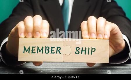Businessman collects wooden puzzles with the words Membership. Belonging of people to the organization, society, association. Business concept Stock Photo