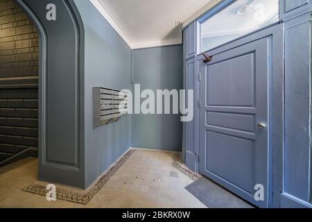 Doorway corridor in old apartment building entrance with mailboxes and newly painted grey walls Stock Photo