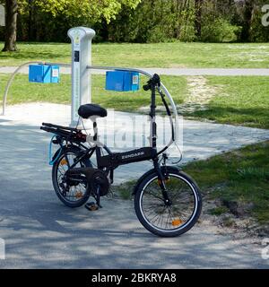 Saolzgitter, Germany, April 12., 2020: Folding bicycle with electric drive in front of a charging station for pedelecs Stock Photo