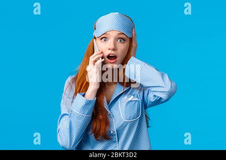 Terrible news. Shocked and concerned young troubled girl hearing bad thing happen, talking on phone, touch head frustrated, gasping drop jaw and stare Stock Photo