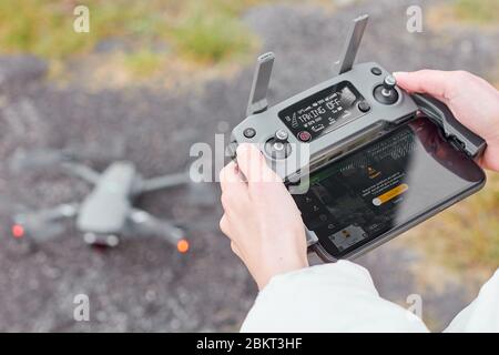 Drone is taking off by remote controller in womans hands. Concept of shooting video in the air. Stock Photo