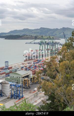 LYTTLETON, NEW ZEALAND - December 02 2019: aerial cityscape with  cranes and containers on quays at industrial harbor, shot in bright cloudy light on Stock Photo