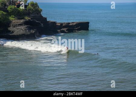 Aerial view of surfer on blue surface of Indian ocean. Riding the waves. Batu Bolong beach on the rocky coast of Bali island, Indonesia. Surfer at the Stock Photo