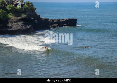 Aerial view of surfer on blue surface of Indian ocean. Riding the waves. Batu Bolong beach on the rocky coast of Bali island, Indonesia. Surfer at the Stock Photo
