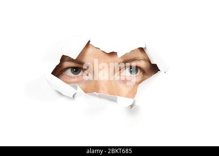 Female Eye looking through hole. Isolated on white background. Spy concept Stock Photo