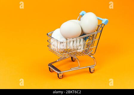 chicken eggs in a shopping cart. isolated on orange Stock Photo