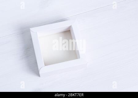 Elegant eco-friendly mockup. Open empty white gift box without a lid on isolated wooden background. Side view, square box. Isolated cardboard box with Stock Photo