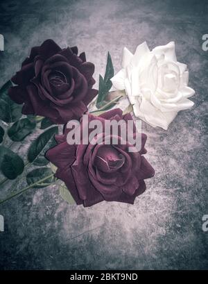 Artificial flowers: three roses on a dark background Stock Photo